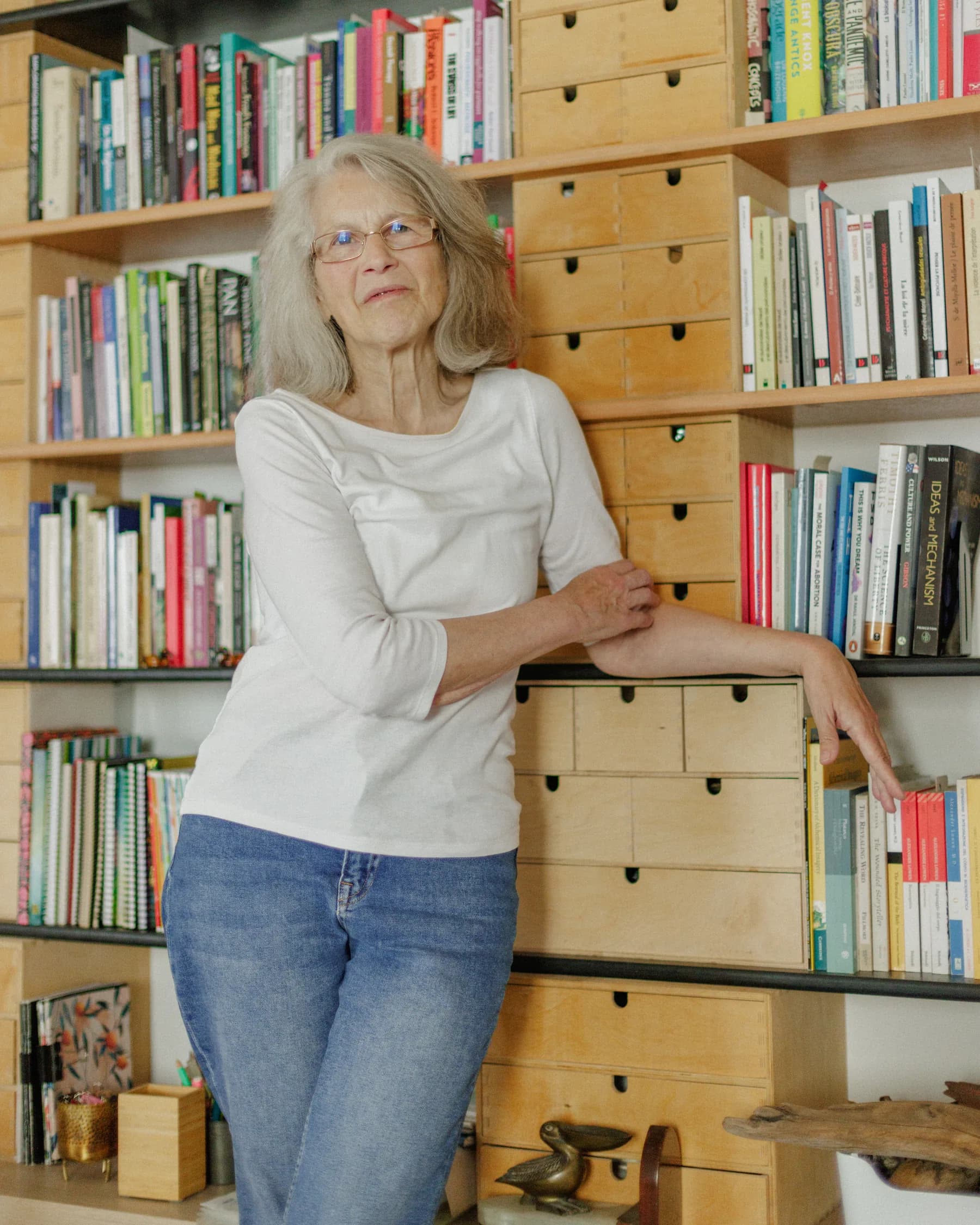 Verónica Blumentals standing by her library of wooden drawers